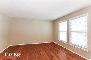 Raymore house for rent - A room with wooden floors and two windows.