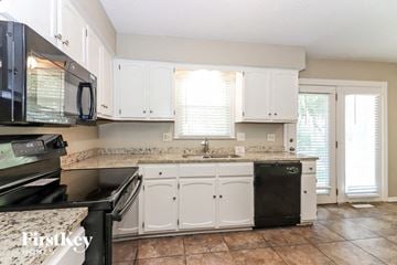 Raymore house for rent - A kitchen with white cabinets and a black dishwasher.