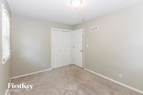 Raymore house for rent - A bedroom with a carpeted floor and a white door.