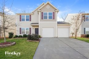 Charlotte house for rent - a beige house with a white garage door and a driveway