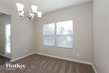 Charlotte house for rent - a living room with two windows and a rug and a chandelier
