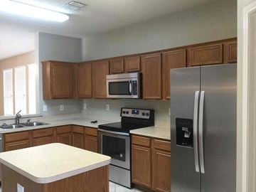 Desoto house for rent - a kitchen with stainless steel appliances and wooden cabinets