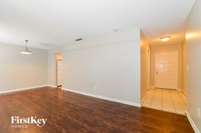 Longwood house for rent - A spacious room with wooden flooring and a white door.