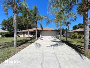 Port Charlotte house for rent - A house with a driveway and palm trees in front.