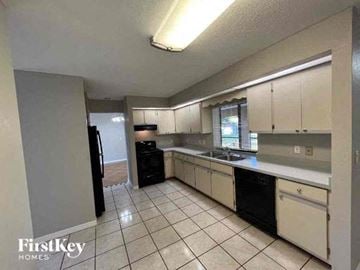 Port Charlotte house for rent - A kitchen with white cabinets and black appliances.