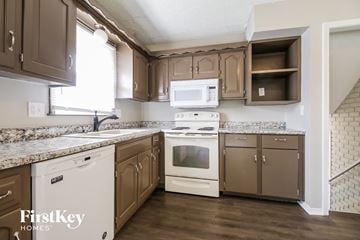 Belton house for rent - a kitchen with white appliances and brown cabinets and granite counter tops
