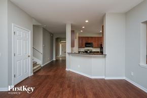 Valrico house for rent - A spacious room with wooden floors and a kitchen area in the background.