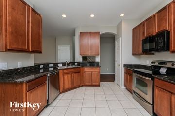 Valrico house for rent - A kitchen with wooden cabinets and black countertops.