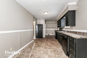 Indianapolis house for rent - a kitchen with black cabinets and granite counter tops and a black refrigerator