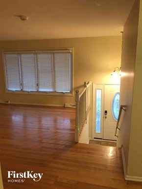 Glenwood house for rent - A wooden floor in a house with a white door and a window with blinds.