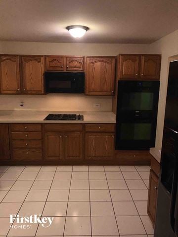 Glenwood house for rent - A kitchen with wooden cabinets and black appliances.