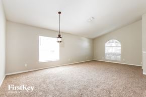 Winter Haven house for rent - A carpeted room with a window and a hanging light fixture.