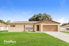 Kissimmee house for rent - a beige house with a lawn and a driveway