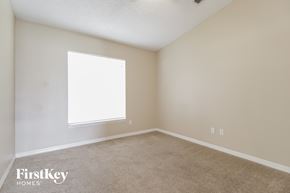 Kissimmee house for rent - a bedroom with a large window and a carpeted floor