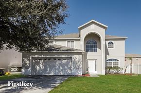 Poinciana house for rent - a white house with a garage and a lawn