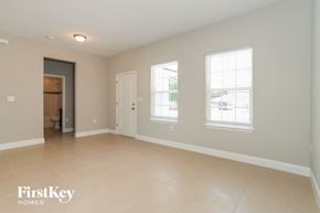 Poinciana house for rent - an empty living room with three windows and a door