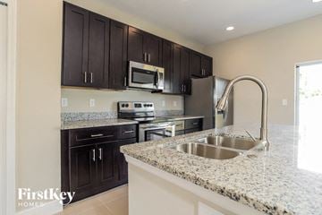 Poinciana house for rent - a kitchen with granite counter tops and black cabinets