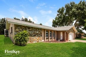 Cape Coral house for rent - A house with a stone wall and a green lawn in front.