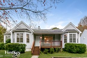 Atlanta house for rent - A house with a porch and a tree with red leaves in front of it.