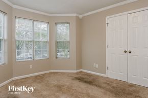 Atlanta house for rent - A room with a carpeted floor, two windows with blinds, and a white door.