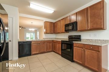 Cape Coral house for rent - A kitchen with brown cabinets and black appliances.