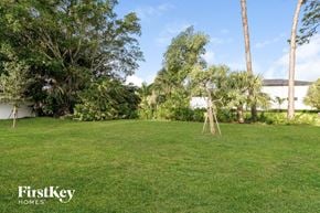Cape Coral house for rent - A lush green lawn with trees and a building in the background.