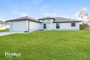 Lehigh Acres house for rent - A white house with a black roof and a green lawn in front.
