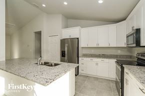 Lehigh Acres house for rent - A kitchen with granite countertops and white cabinets.