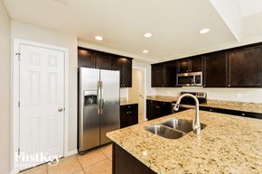 Cape Coral house for rent - a kitchen with granite counter tops and a stainless steel refrigerator