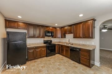 Lancaster house for rent - A kitchen with brown cabinets and a black refrigerator.