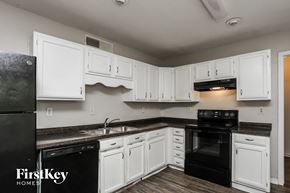 Desoto house for rent - A kitchen with white cabinets and black appliances.