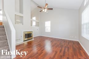 Raymore house for rent - A room with a wood floor and a fireplace.
