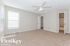 Raymore house for rent - A spacious room with a ceiling fan and carpeted floor.