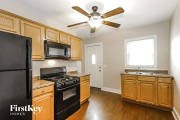 Aurora house for rent - A kitchen with wooden cabinets and a black fridge.