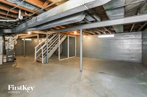 Waukegan house for rent - A spacious basement with a staircase and a pipe running along the wall.