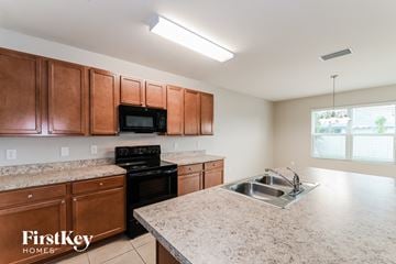 Cape Coral house for rent - a kitchen with wood cabinets and granite counter tops and a sink