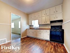 Joliet house for rent - an empty kitchen with white cabinets and a black stove and oven