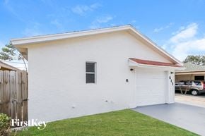Lake Worth house for rent - A white house with a red roof and a garage door is shown.