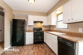 Excelsior Springs house for rent - a kitchen with white cabinets and black appliances and a counter top