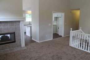 Raymore house for rent - A living room with a fireplace and a baby crib.