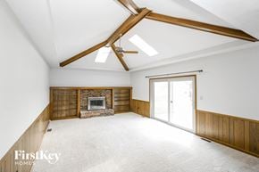 Noblesville house for rent - A spacious room with a fireplace and a ceiling fan.