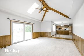 Noblesville house for rent - A spacious room with a ceiling fan and sliding glass doors.