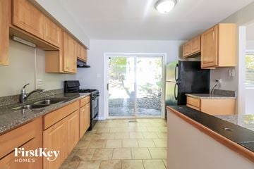 University Park house for rent - a kitchen with wooden cabinets and a door to the backyard