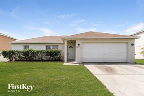 Kissimmee house for rent - a white house with a garage door and a lawn