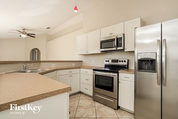 Kissimmee house for rent - a kitchen with stainless steel appliances and white cabinets