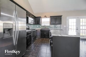 Raymore house for rent - a large kitchen with black cabinets and stainless steel appliances