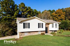 Birmingham house for rent - a small white house with a stone foundation and a yard with trees