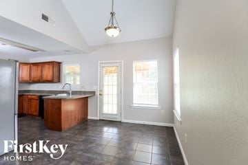 Calera house for rent - a kitchen with wood cabinets and tile flooring and a sink