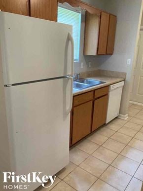 Jonesboro house for rent - A white refrigerator in a kitchen with wooden cabinets.