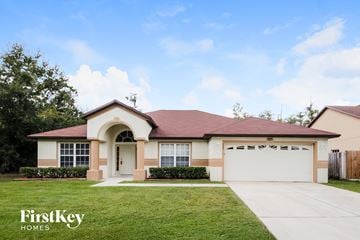 Kissimmee house for rent - a beige house with a driveway and a lawn